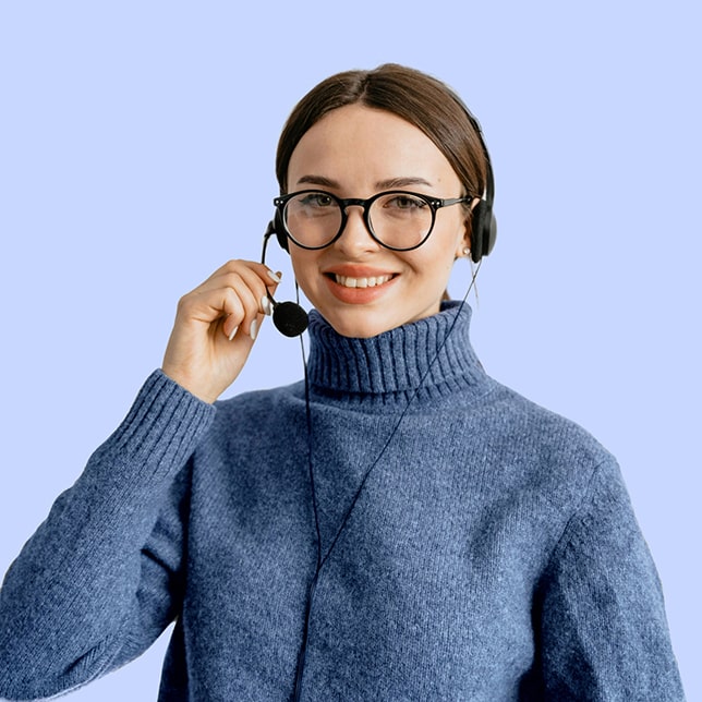 A dark-haired woman in a blue turtleneck, wearing glasses and a headset.