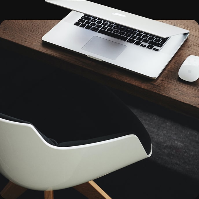 En kontorstol og en laptop på et bord