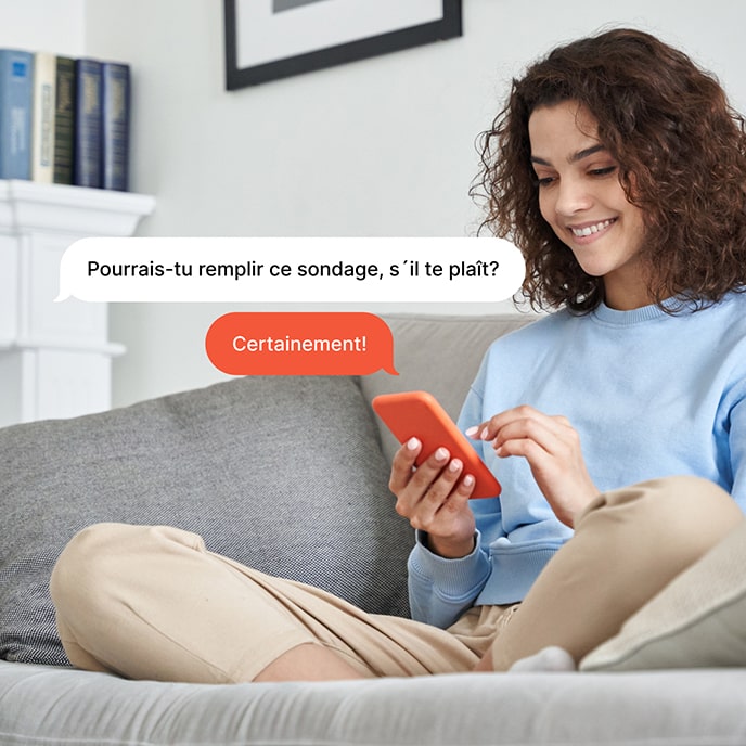 Une fille assise sur un canapé, répondant à une enquête sur son téléphone portable