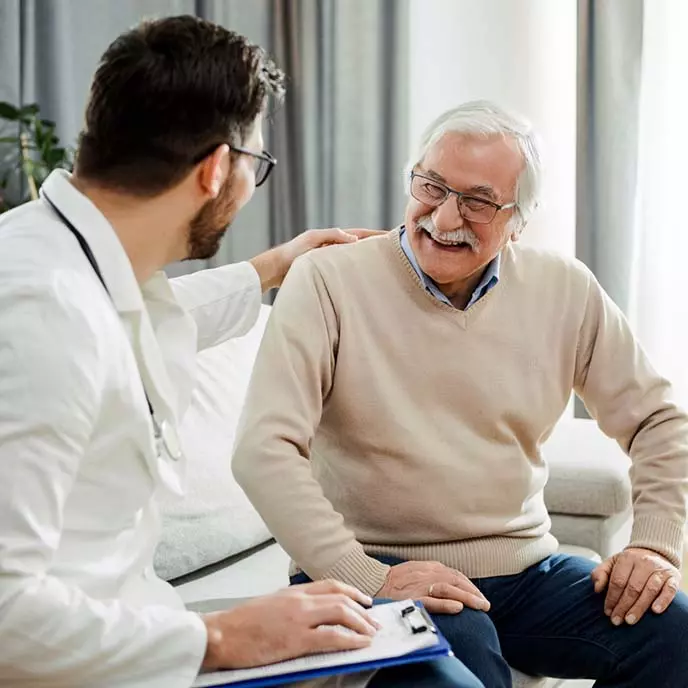 Bendrosios praktikos gydytojas pasakoja savo pacientui medicininio tyrimo rezultatus. Abu šypsosi.